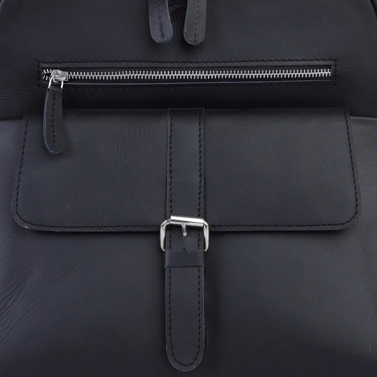Black backpack with a front pocket and zipper on a light gray background