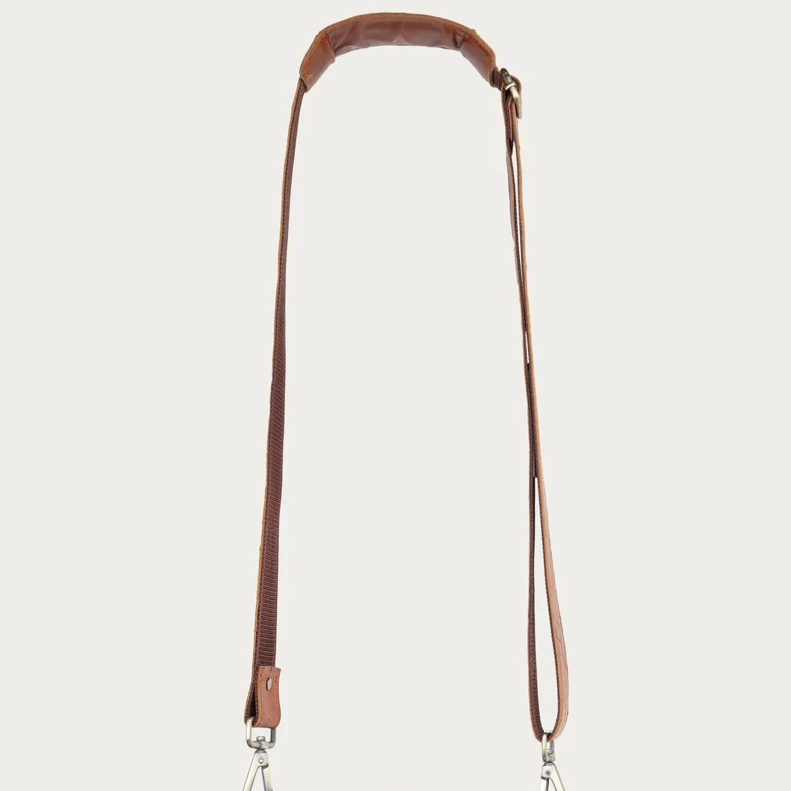 tan leather satchel bag with a strap on a light gray background