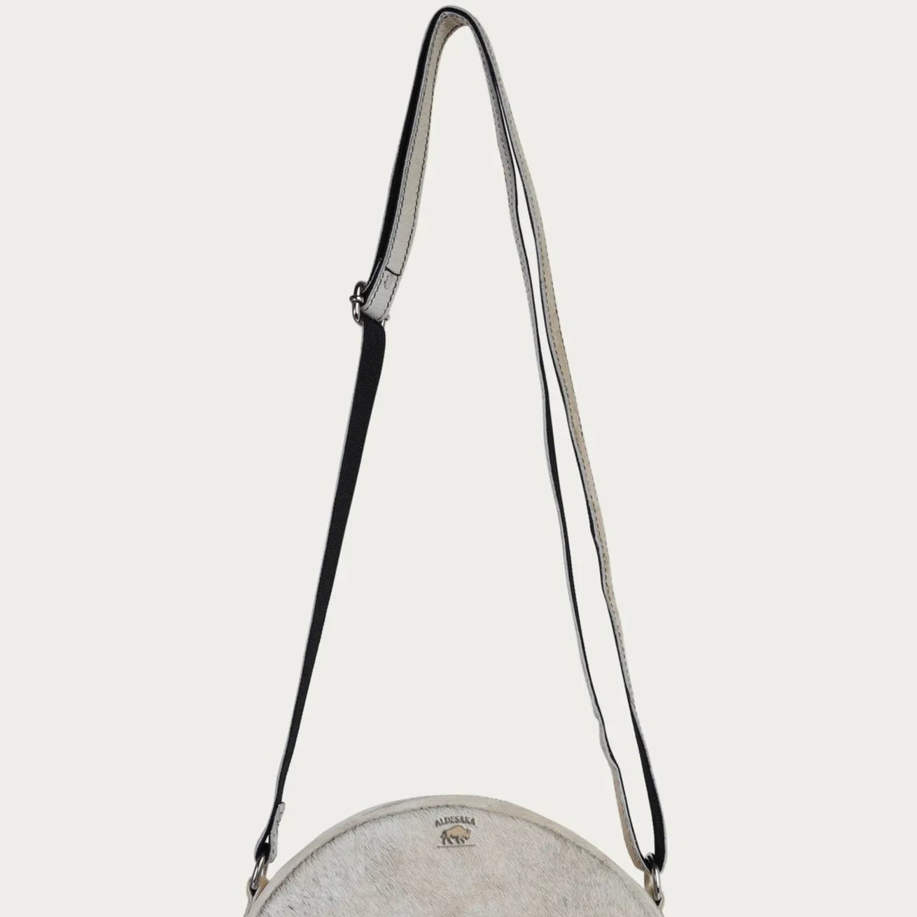 Round crossbody bag with a strap on a light gray background