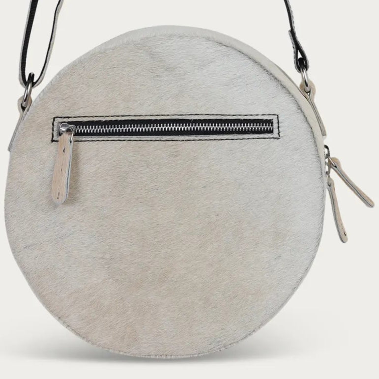 Round white hairon crossbody bag with a black zipper on a light gray background