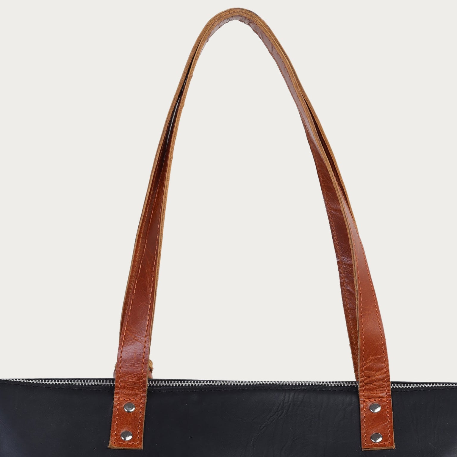 Black tote bag with brown handles on a white background