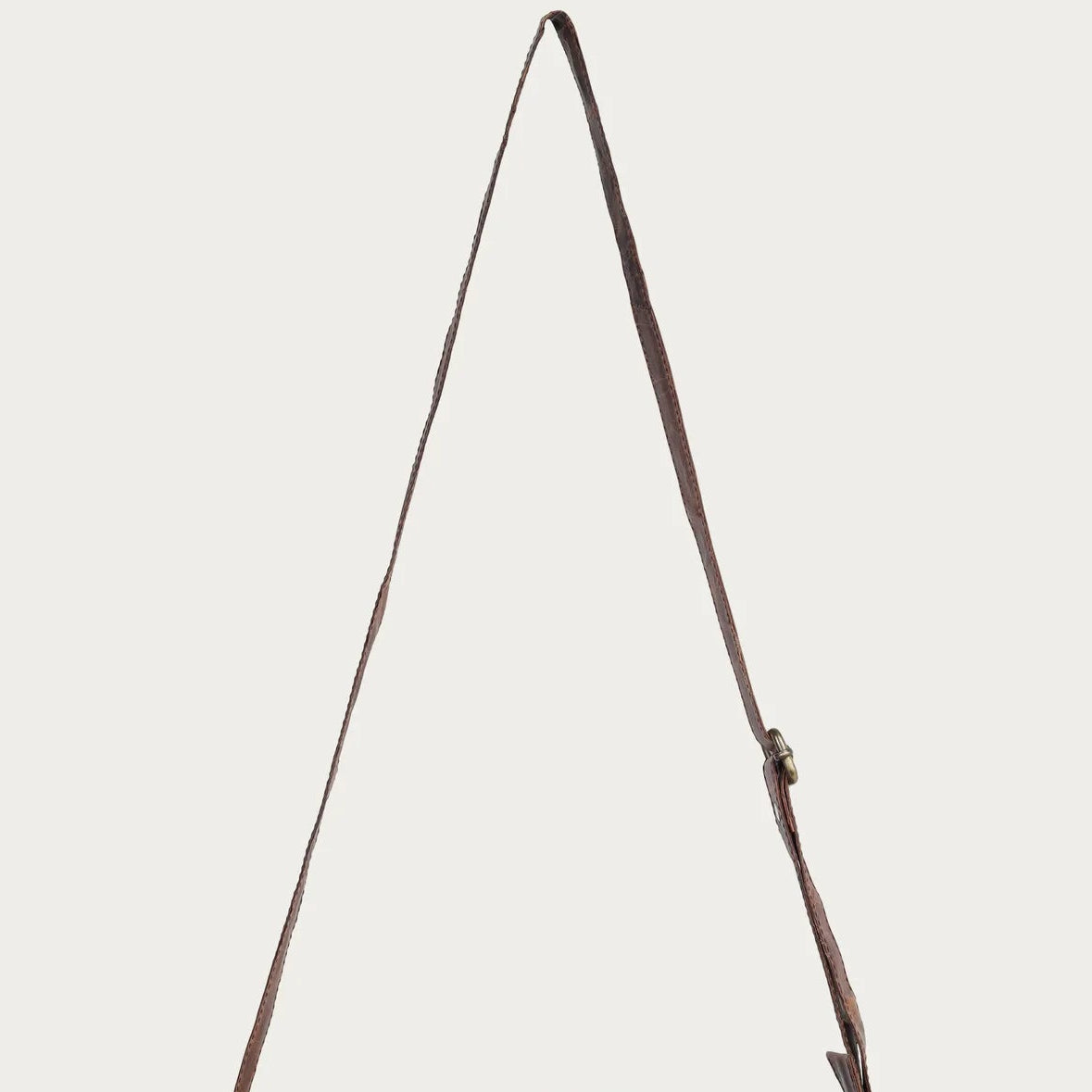 Brown leather bag with a strap on a light gray background