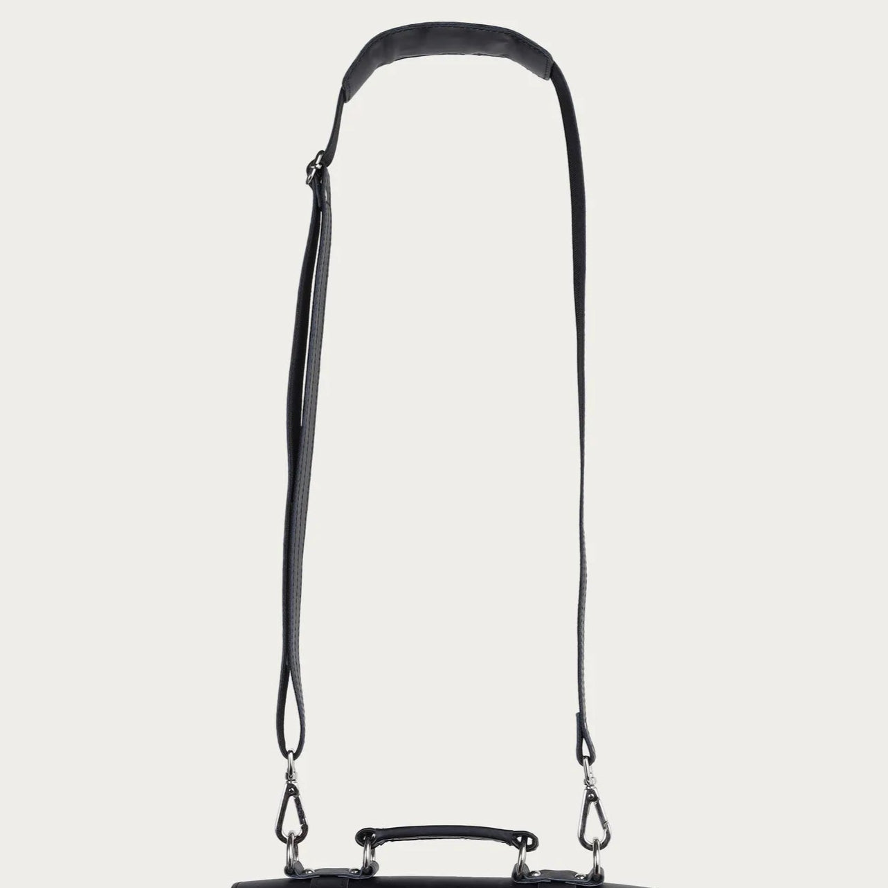 Black leather satchel bag with a strap on a light gray background
