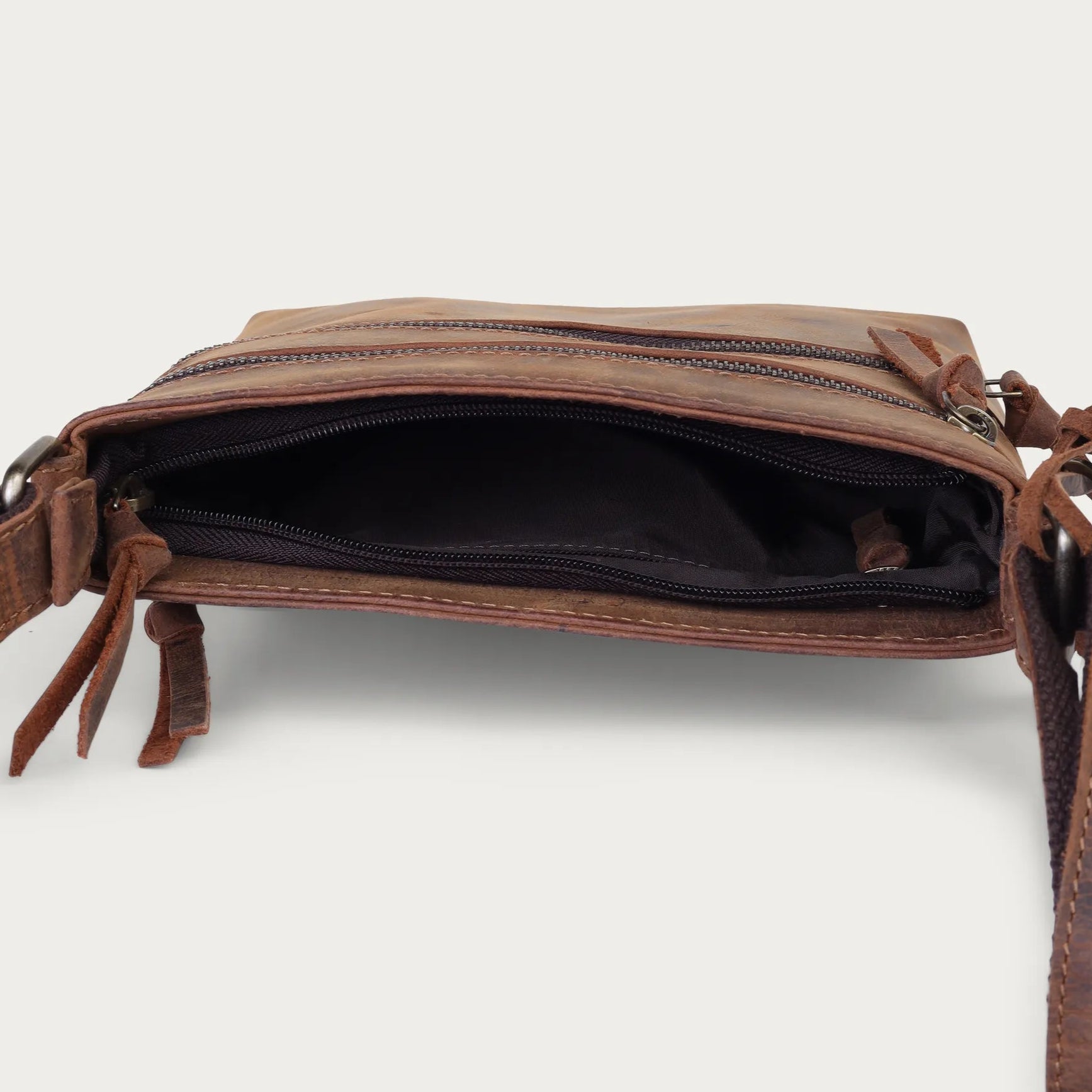 Brown leather bag with a strap on a light beige background