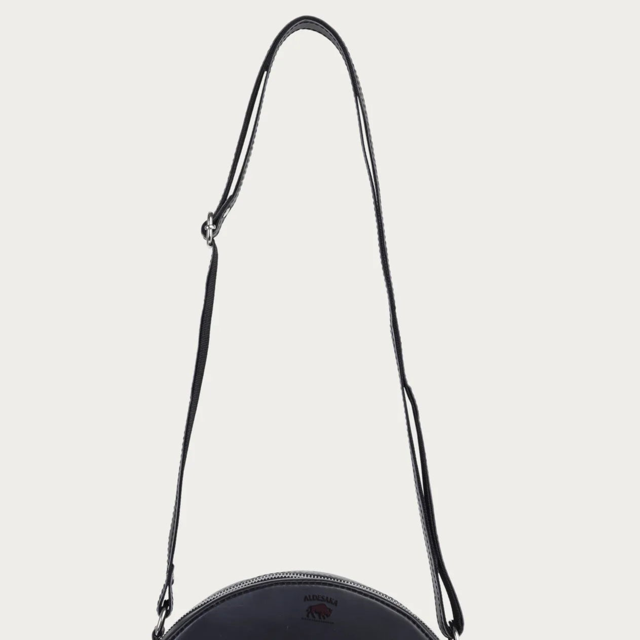 Black round handbag with a strap on a light gray background