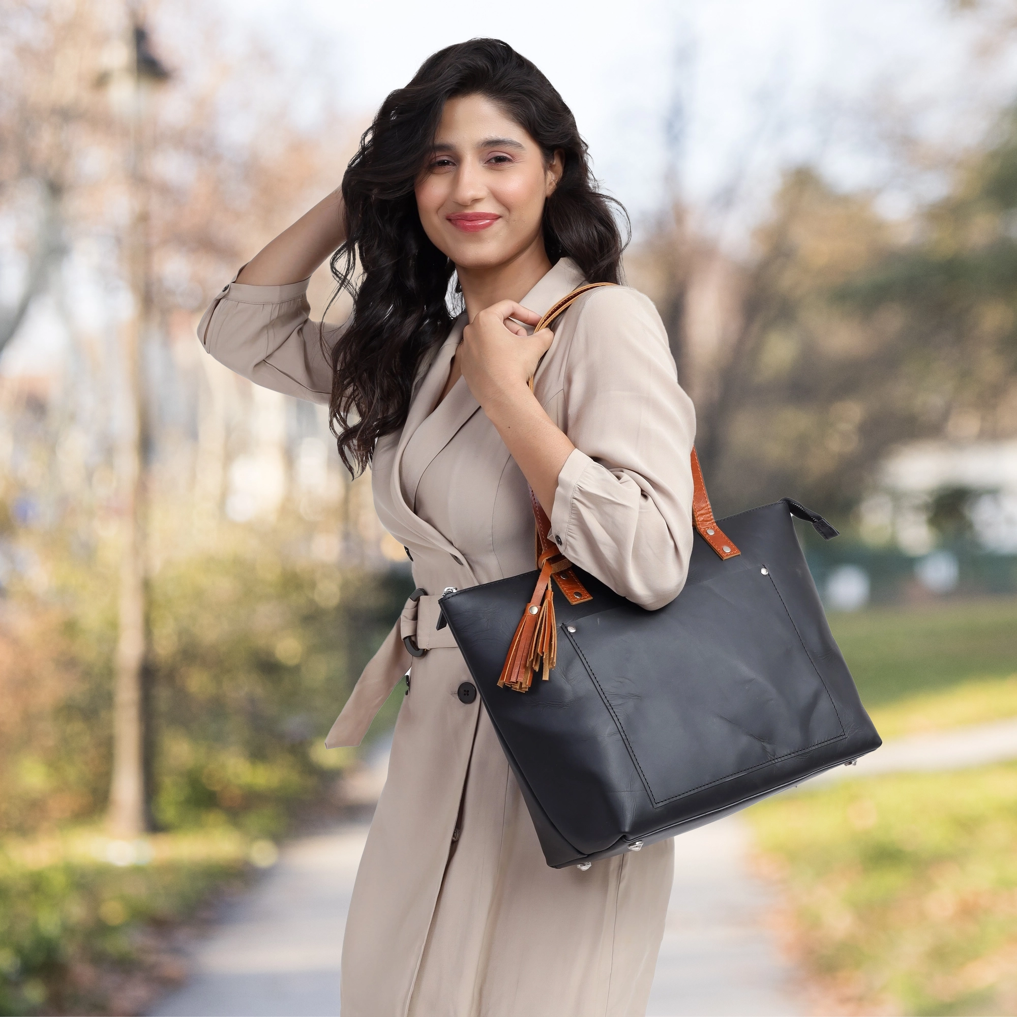 Woman carrying luxury leather tote bag in neutral outfit

