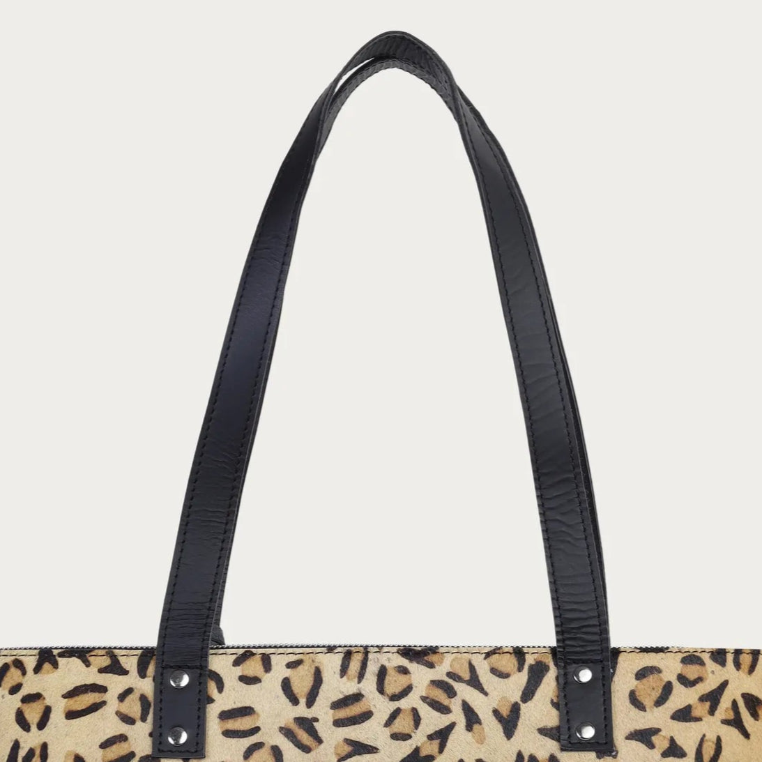 Leopard print tote bag with black handles on a light gray background