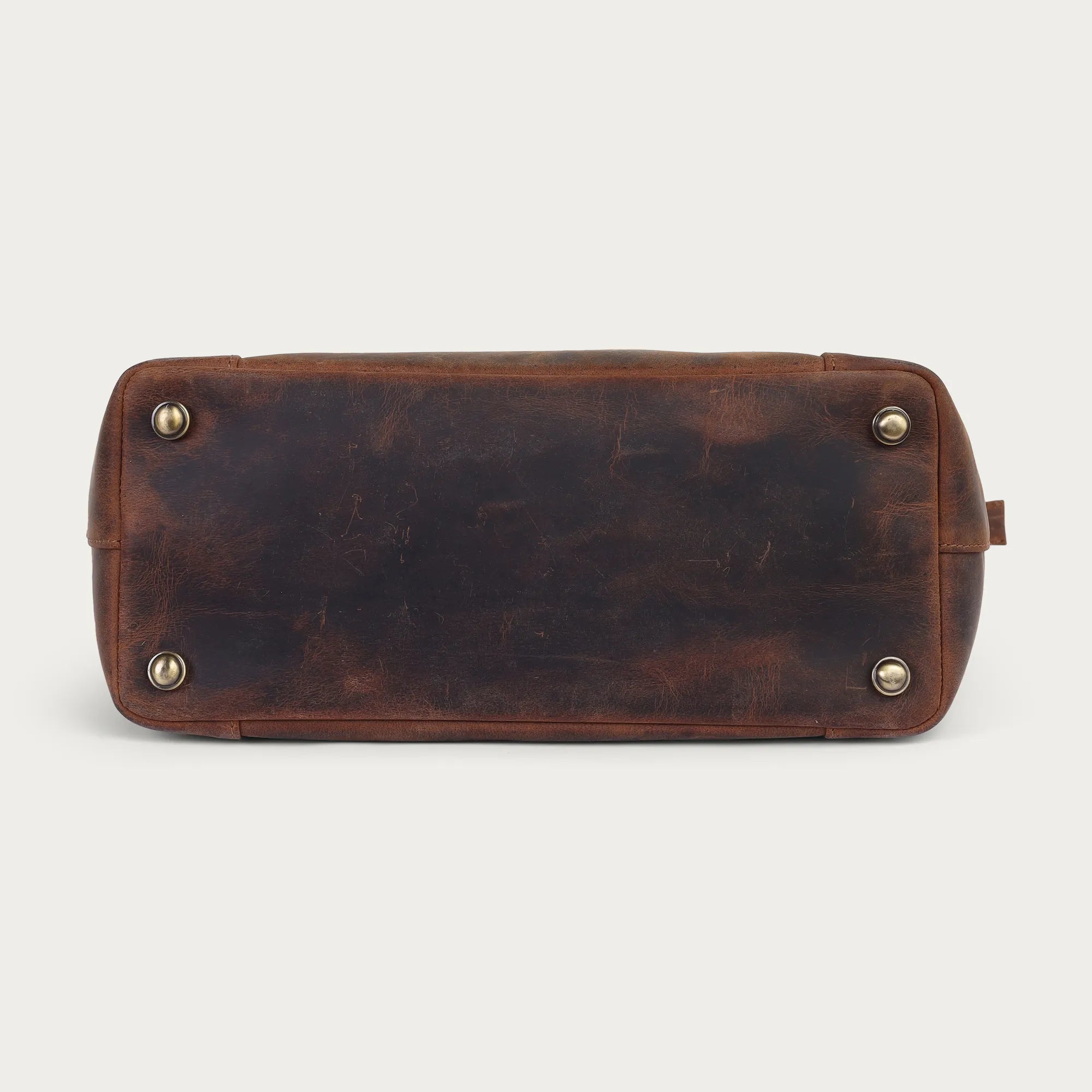 Brown leather bag with gold studs on a light gray background