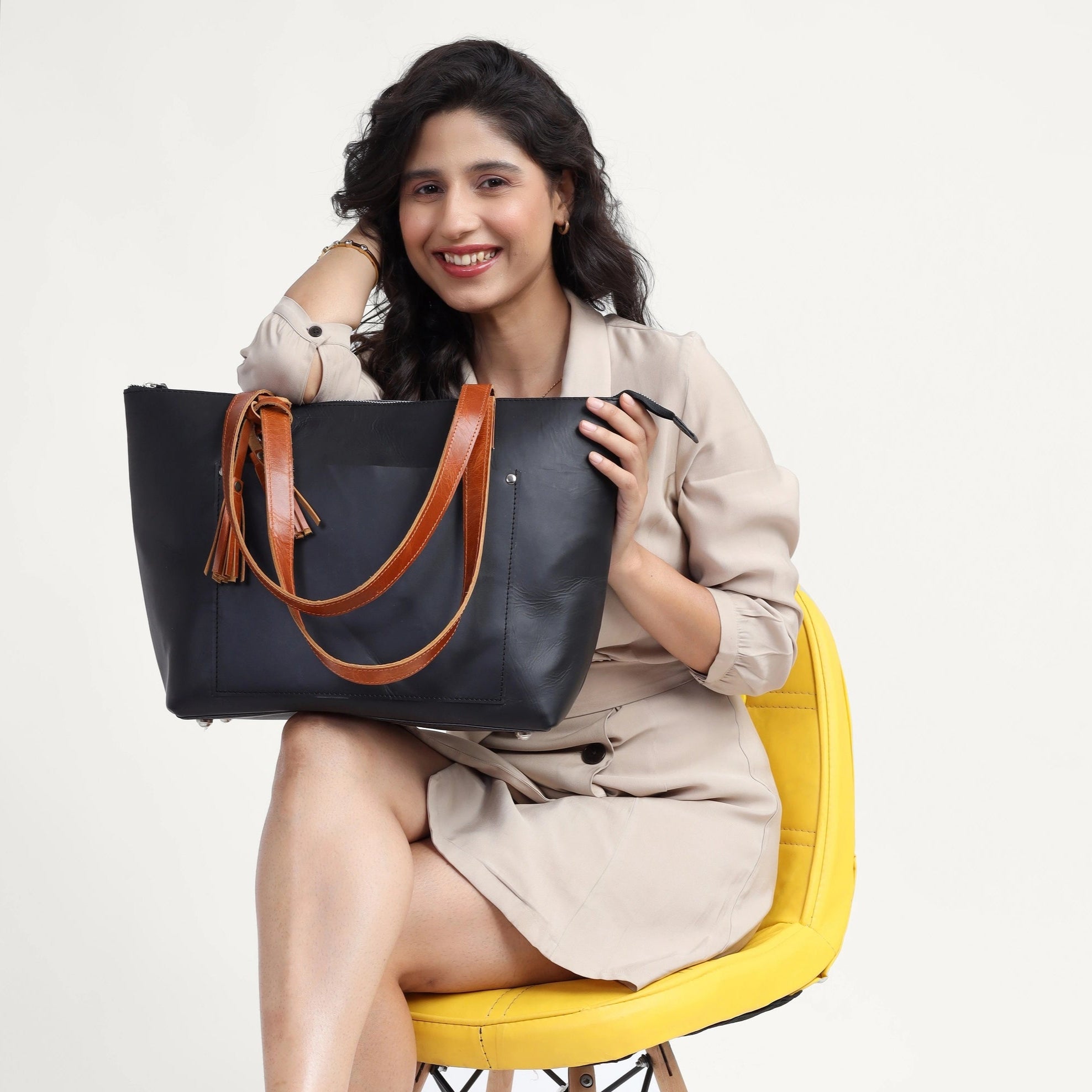 Woman holding a black leather handbag with brown handles on a white background