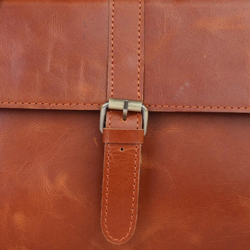Tan leather backpack on a light gray background