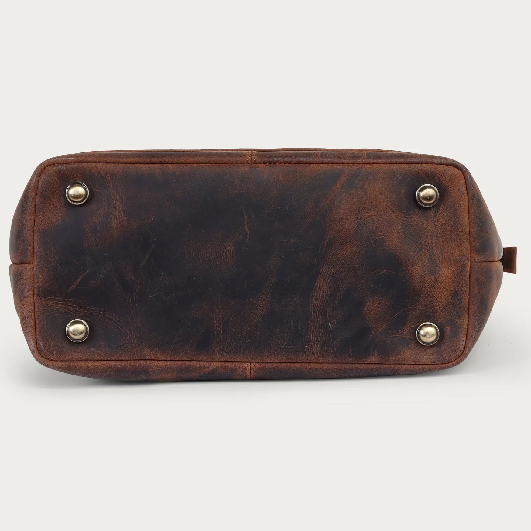 Brown leather bag with gold studs on a light gray background