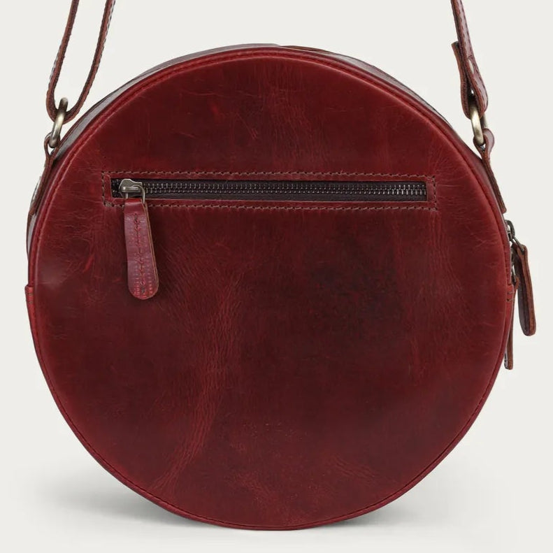 Round wine leather bag with a strap on a light gray background