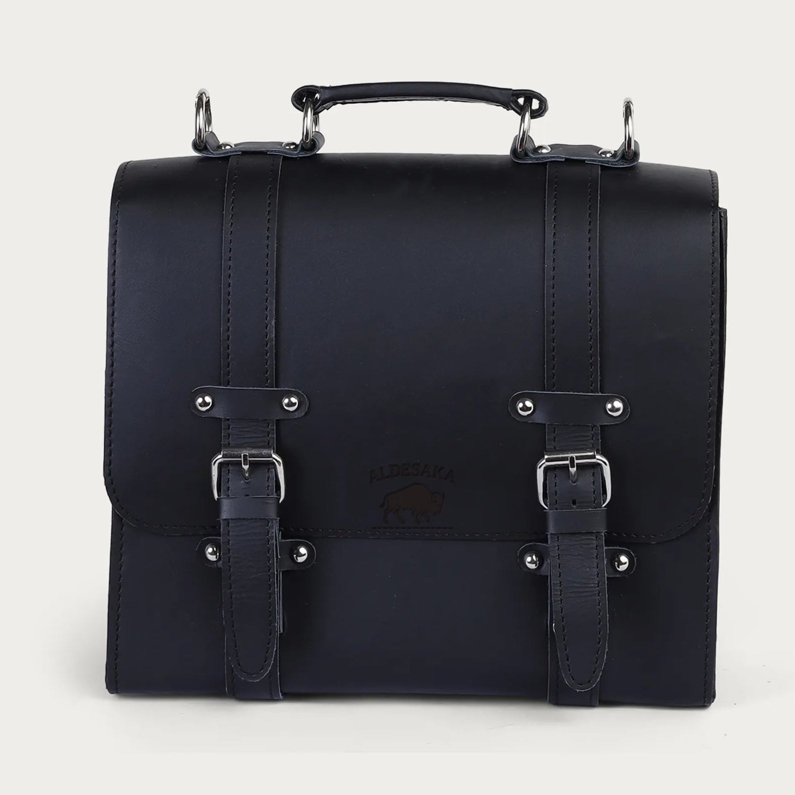 Black leather satchel bag with silver buckles on a light gray background