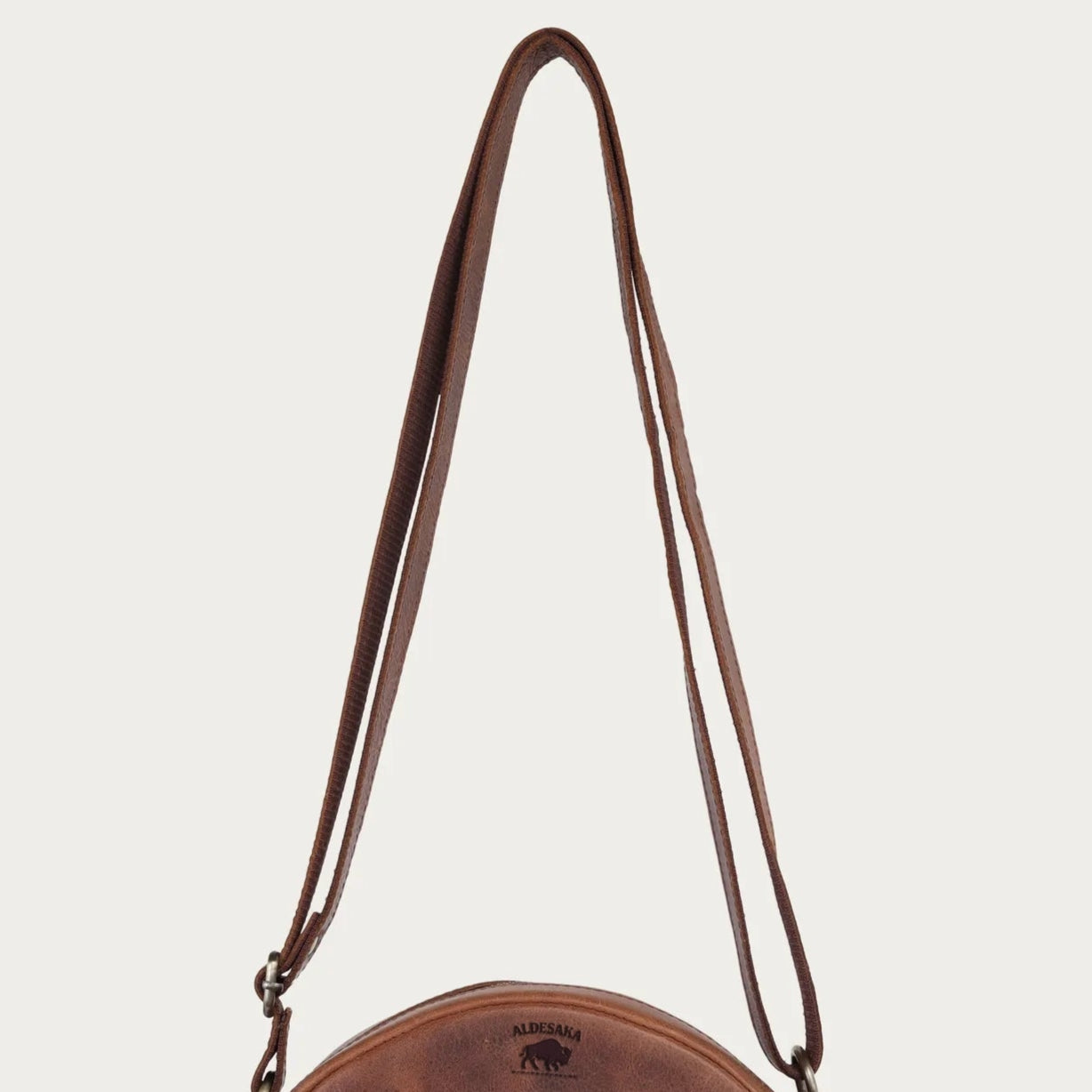 distress Brown leather crossbody bag on a light beige background