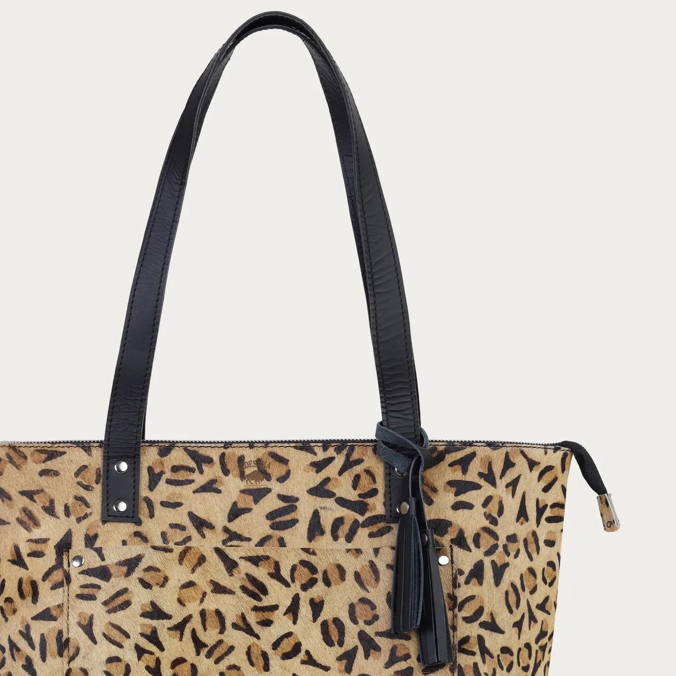 Leopard print tote bag with black handles on a light beige background